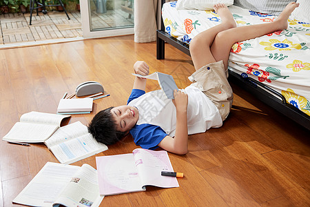 在复习的男孩躺在地板上看书的男孩背景