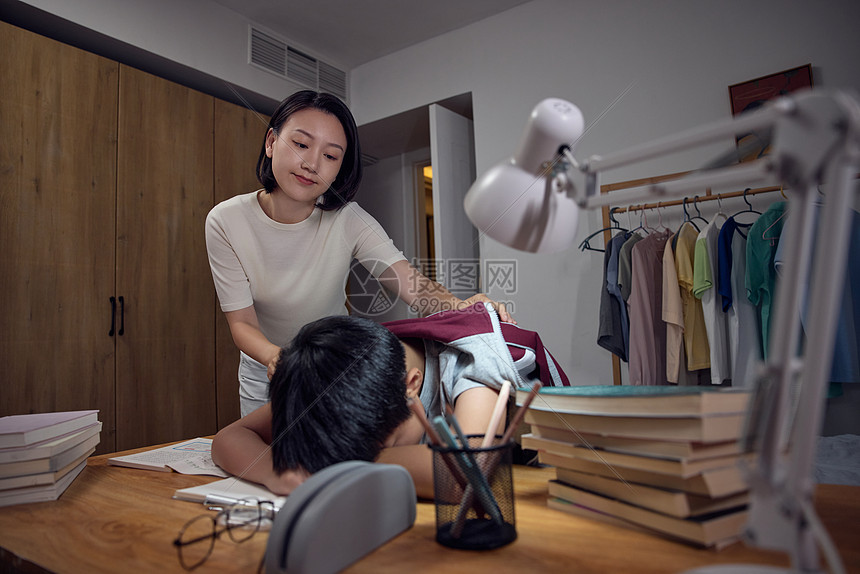 妈妈为疲惫睡着的男孩披上衣服图片