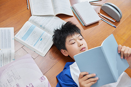 小学生看书躺在地板上看书的男孩背景
