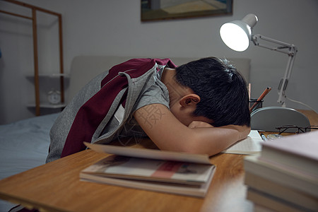 台灯学习趴在书桌上睡觉的男孩背景