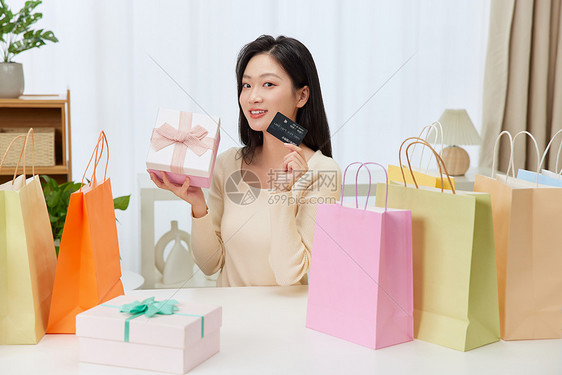 美女开心地展示礼物盒与购物卡图片