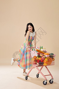 年轻美女推着装满蔬菜的购物车图片