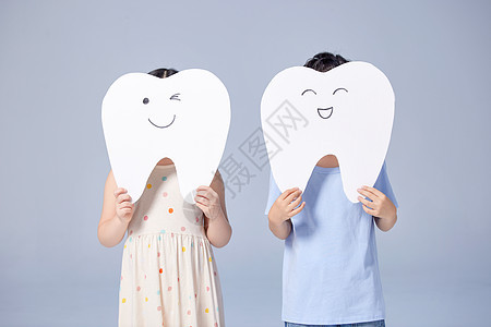 两个小朋友用牙齿模型手举牌挡住脸图片