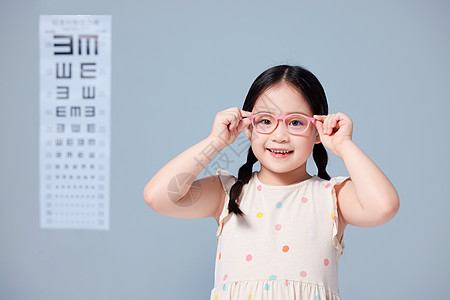 小女孩在视力表前戴上新眼镜背景