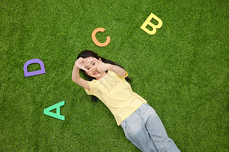 小女孩躺在有英文字母的草地上图片