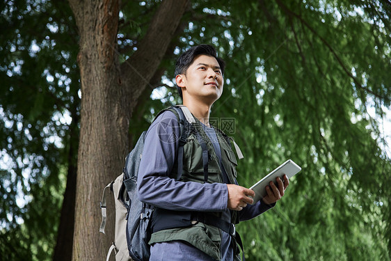 森林里徒步拿着平板的男性图片