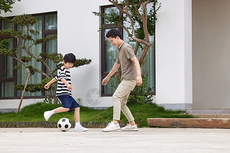 爸爸和儿子在院子里踢足球图片