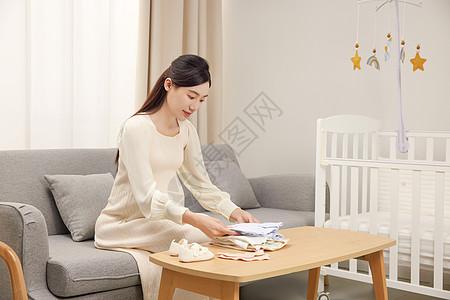 客厅里叠婴儿衣服的孕妇图片
