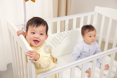 婴儿床上开心玩耍的双胞胎图片