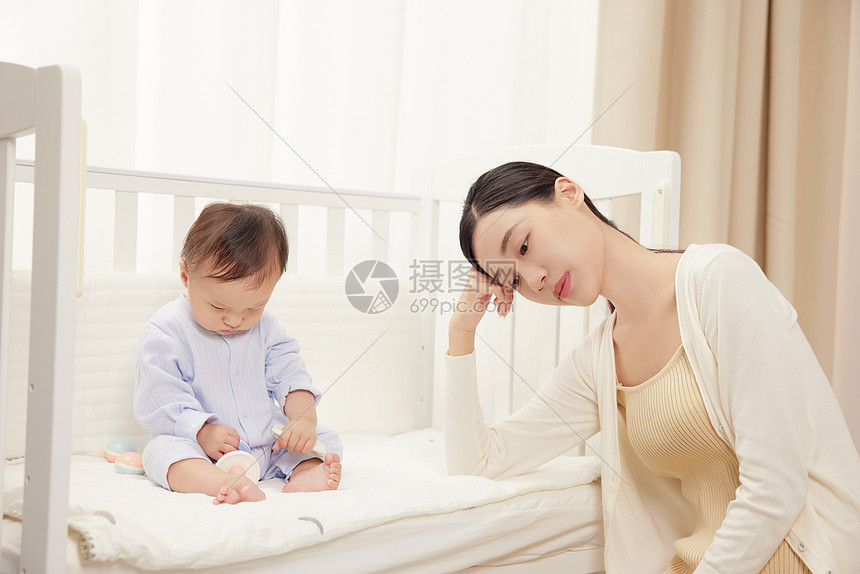 疲惫的妈妈和婴儿床里的宝宝图片