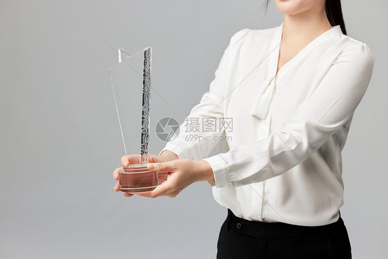 手拿奖杯的商务女性手部特写图片