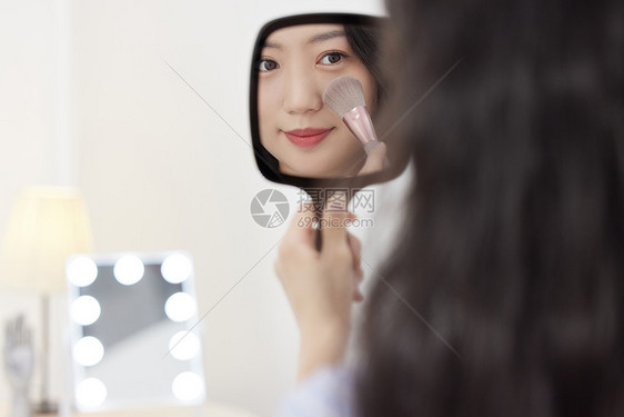 照镜子化妆的年轻美女图片
