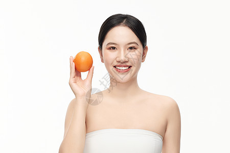 穿着抹胸的女人举着一个橙子拍照背景图片
