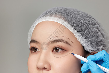 整形医生用记号笔给女人脸上做标记图片