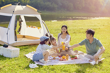 户外游玩一家人坐在草地上露营干杯背景