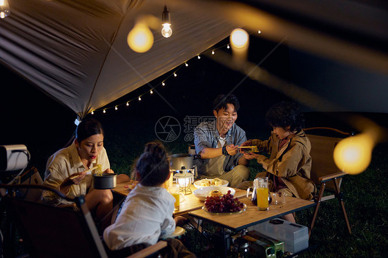 一家人在草地上露营吃晚餐图片