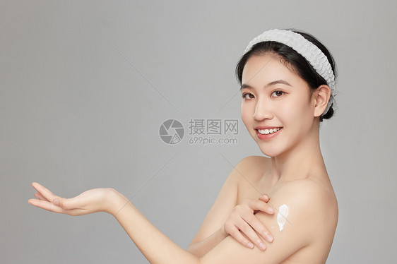 微笑展示手臂上身体乳的年轻女孩图片