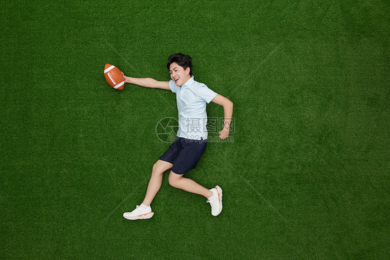 创意俯拍手上拿着橄榄球的热血青年图片