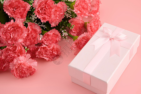 粉色底纹一大束娇艳欲滴的红色康乃馨和粉色蝴蝶结礼物盒背景