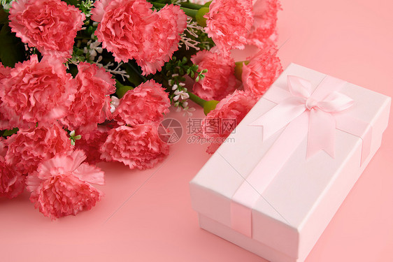 一大束娇艳欲滴的红色康乃馨和粉色蝴蝶结礼物盒图片
