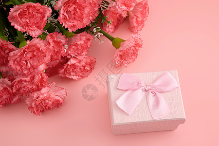 一大束娇艳欲滴的红色康乃馨和粉色蝴蝶结礼物盒背景图片