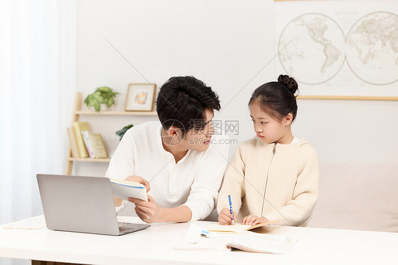 正在指导女儿作业的年轻爸爸图片