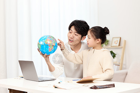 拿着地球仪的爸爸正温柔给女儿讲解地理知识图片