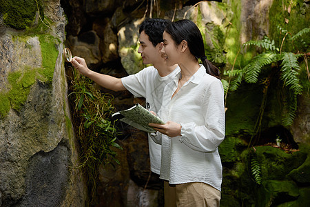 一对情侣在植物园拿着放大镜观察植物图片