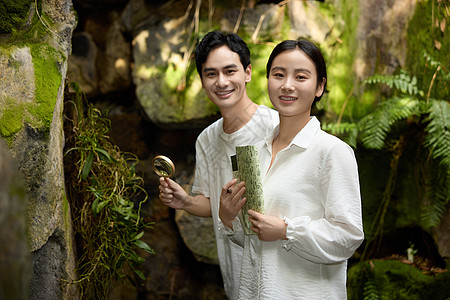 一对情侣在植物园拿着放大镜观察植物图片