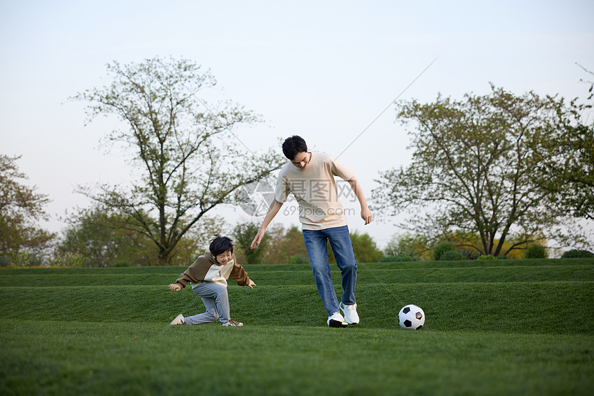 父子在户外踢足球玩耍图片