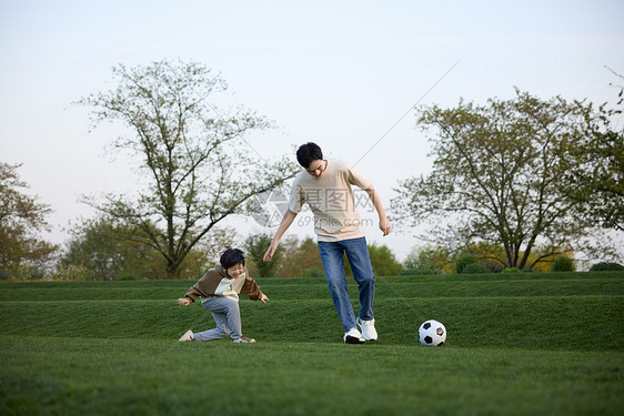 父子在户外踢足球玩耍图片