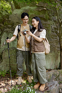 老年人登山漂亮女孩给男朋友看相机里拍的山上景色背景