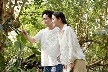 植物园里仔细观察的年轻情侣图片