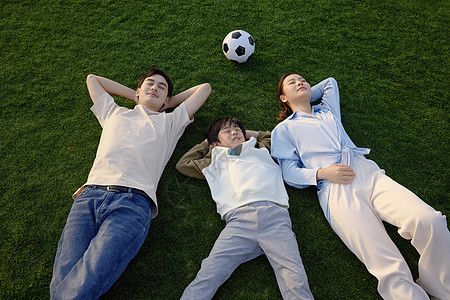 运动后躺在草坪上放松的一家三口图片