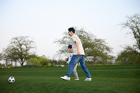 正在草坪上奔跑追球的父子俩图片