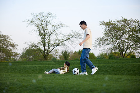 躺在草坪上的小男孩和在旁边玩球的父亲图片