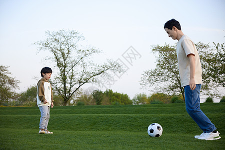 在草坪上玩足球游戏的父子俩图片