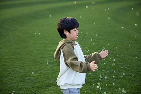 在草坪上玩泡泡的小男孩图片
