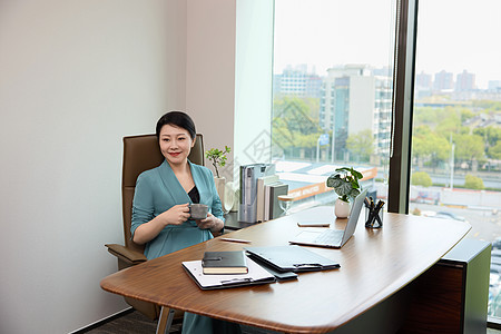 女白领坐在办公室电脑前喝咖啡图片