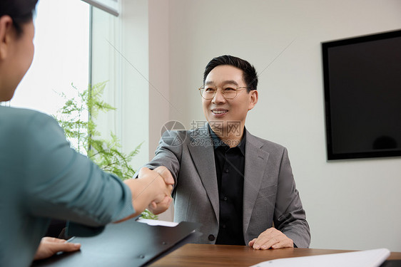 两位白领在办公室握手达成合作图片