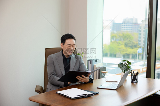 一位男白领坐在办公室看文件图片