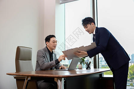 一位商务男性在办公室给领导看文件图片