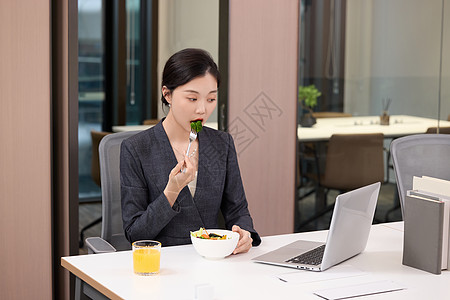 办公室里正在吃轻食的女职员图片