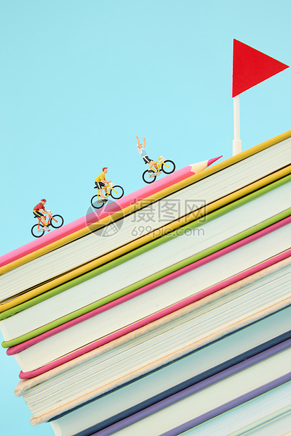 彩色书籍上骑行的创意微距小人图片