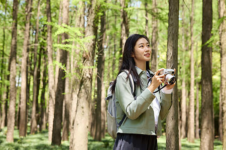 拿着相机在公园里拍摄美景的女孩图片