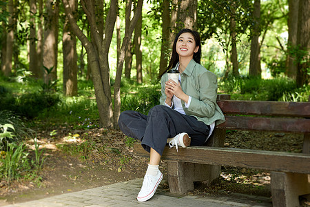 拿着咖啡杯坐在公园长椅上的美女图片