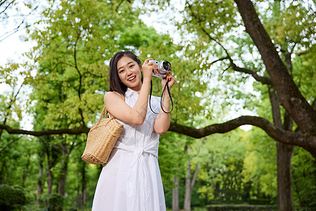 在森林里拿着相机拍照的女孩形象图片