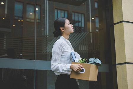 搬着一箱离职物品的女职员离开公司图片