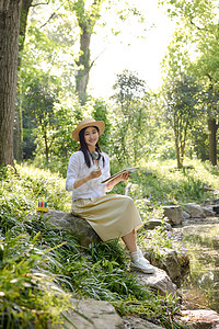 森林里美女坐在石头上写生图片