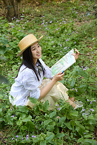 坐在草丛中戴着草帽画画的美女侧视图图片